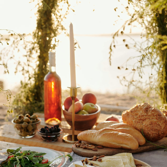 Outdoor scene charcuterie, bread, and wine adorns a gorgeous table in the Italian countryside